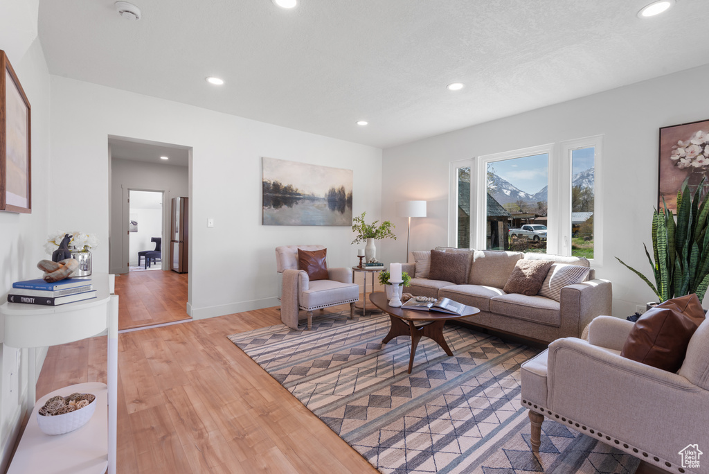 Living area with baseboards, light wood finished floors, and recessed lighting