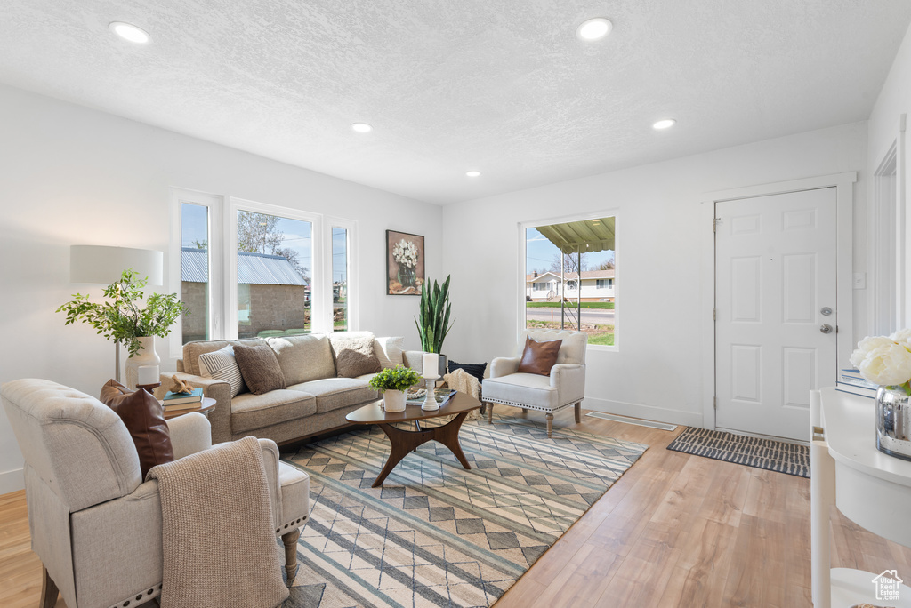 Living area featuring recessed lighting, plenty of natural light, a textured ceiling, and wood finished floors