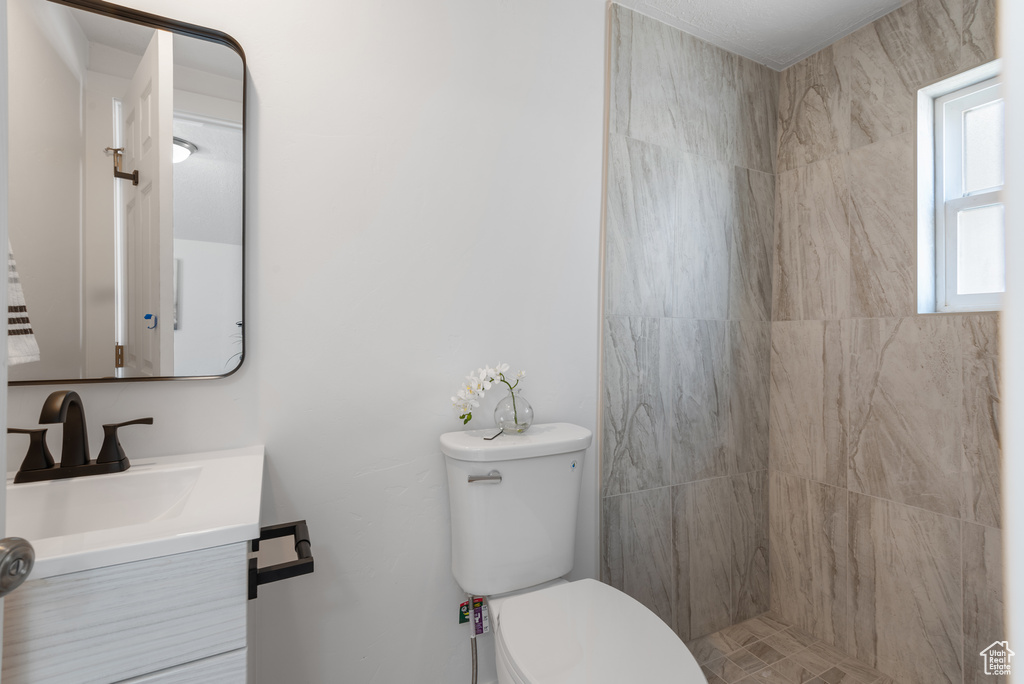 Bathroom with a tile shower, toilet, and vanity