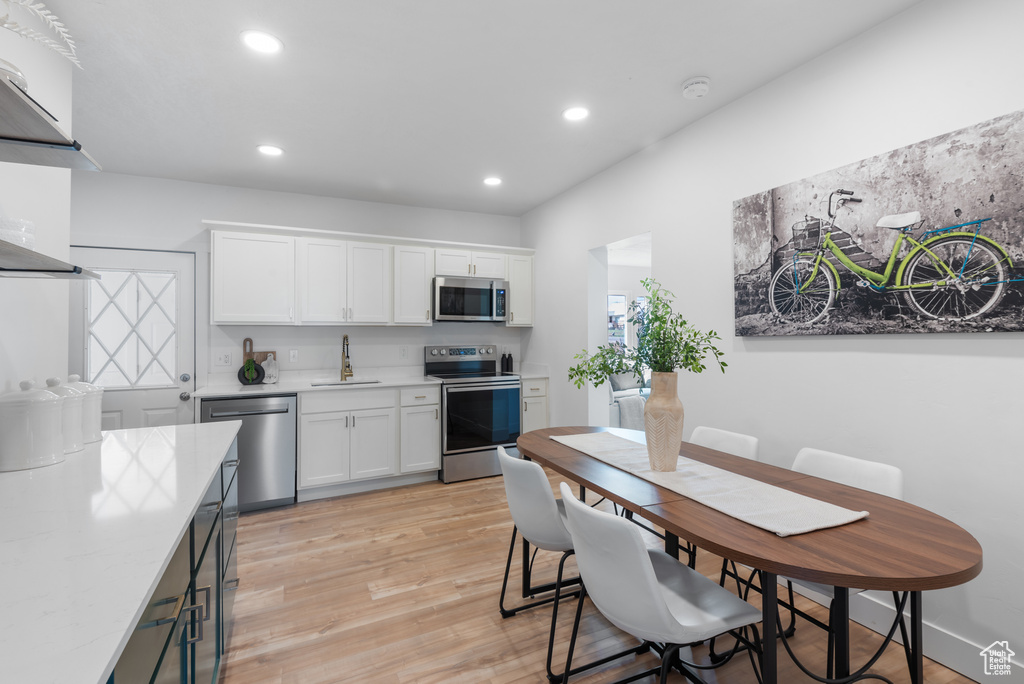 Kitchen featuring a sink, light wood finished floors, white cabinets, appliances with stainless steel finishes, and recessed lighting