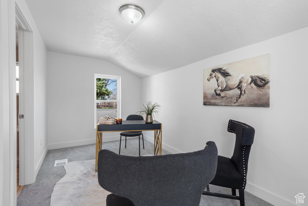 Carpeted office with vaulted ceiling, a textured ceiling, visible vents, and baseboards