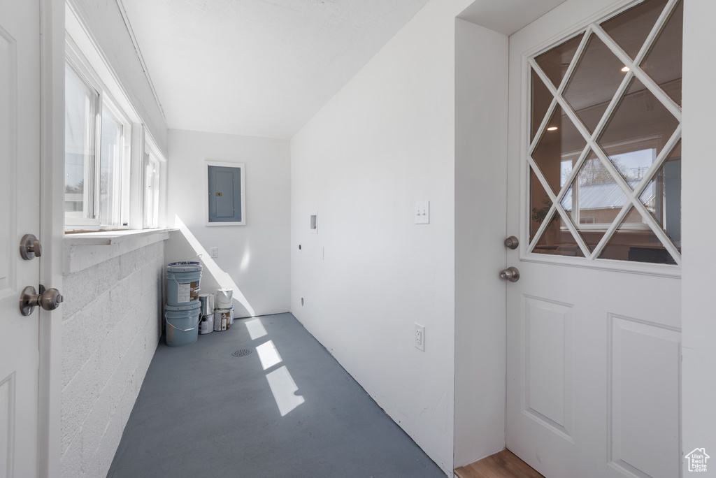 Interior space with concrete floors, electric panel, and a healthy amount of sunlight
