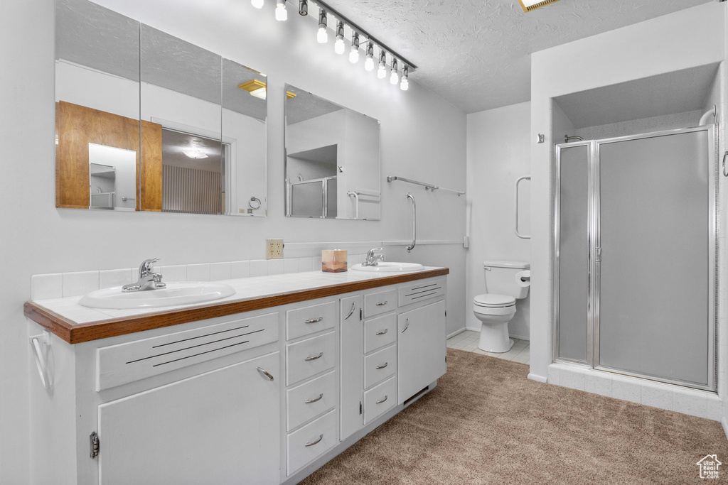 Full bath with a sink, a stall shower, toilet, and double vanity