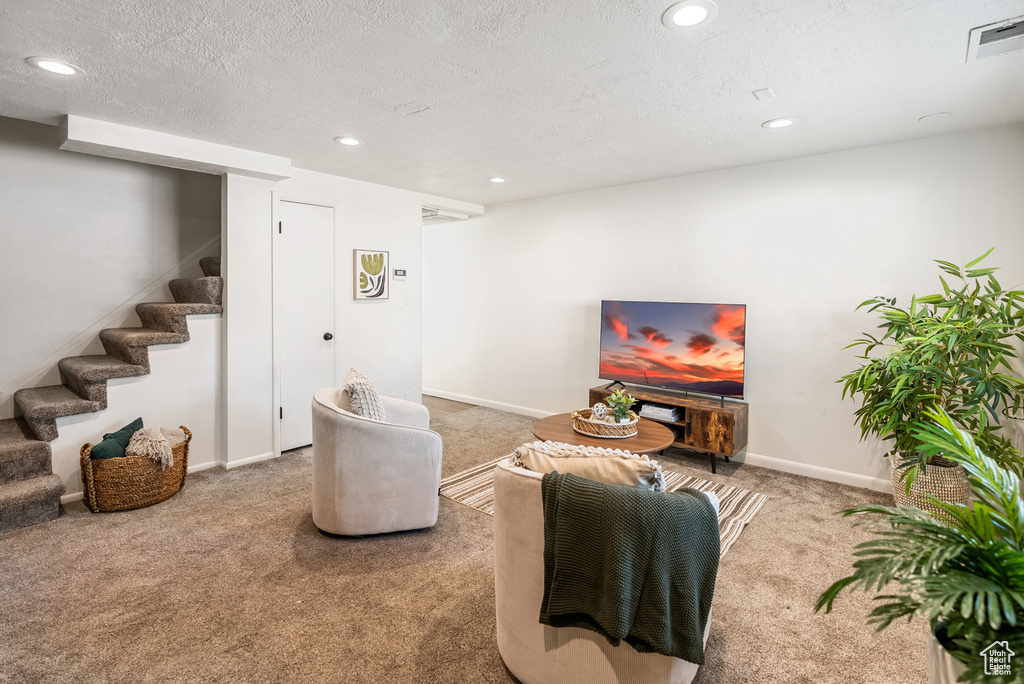 Living room with carpet, stairway, recessed lighting, baseboards, and a textured ceiling