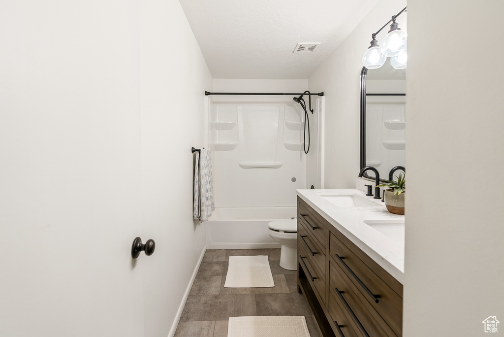 Full bath with double vanity, toilet, shower / tub combination, baseboards, and wood finished floors
