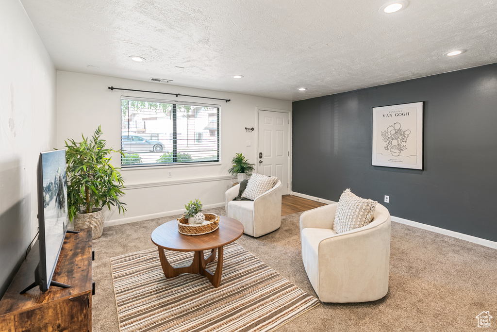 Carpeted living room with recessed lighting, a textured ceiling, and baseboards