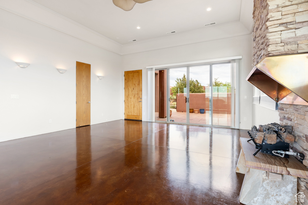 Living area with a ceiling fan, visible vents, crown molding, concrete floors, and a high ceiling