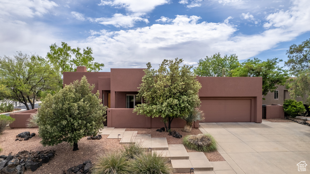 Pueblo-style home with stucco siding, driveway, and a garage