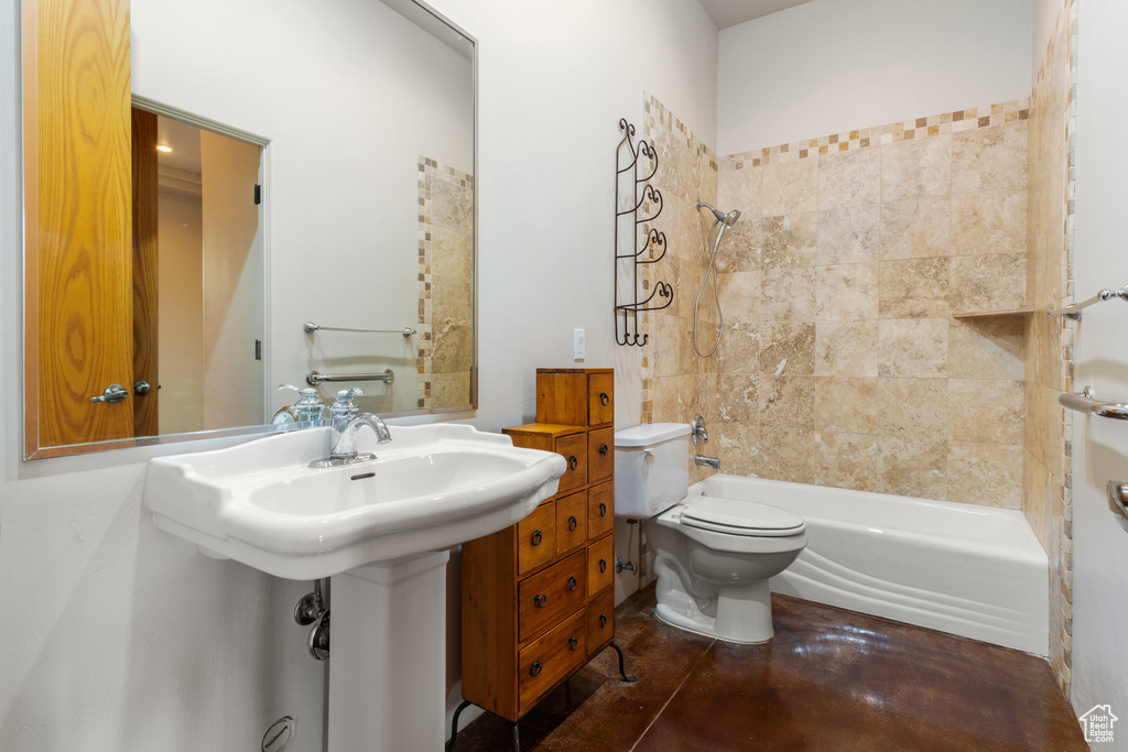 Bathroom with finished concrete flooring, bathtub / shower combination, and toilet