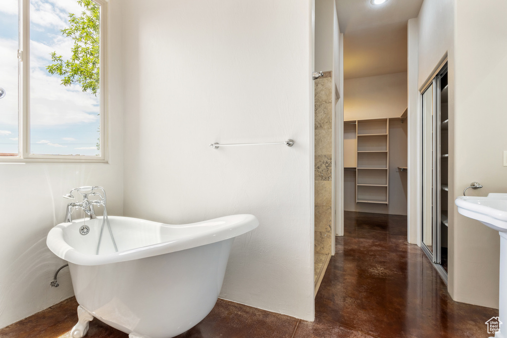 Full bathroom featuring a freestanding bath and finished concrete flooring