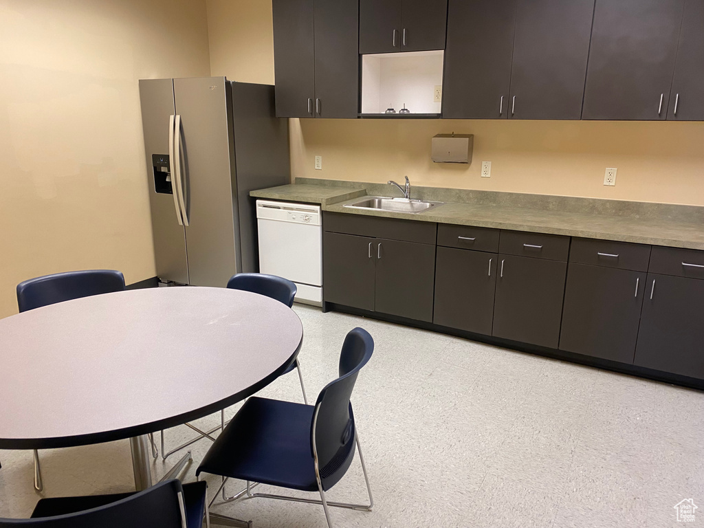 Kitchen featuring dishwasher, stainless steel refrigerator with ice dispenser, a sink, and light flooring