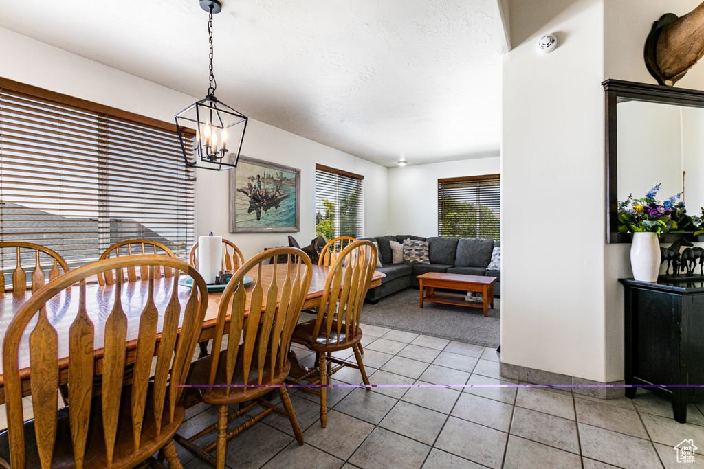 Dining area featuring light colored carpet, light tile patterned flooring, and a chandelier