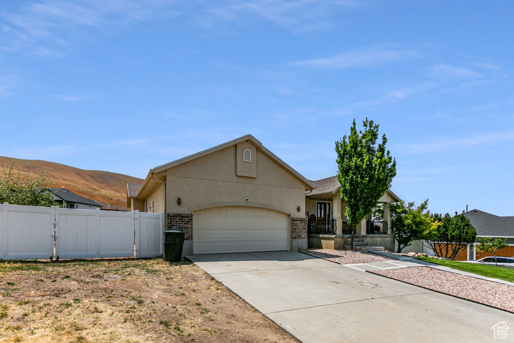 Single story home with a gate, driveway, an attached garage, fence, and stucco siding