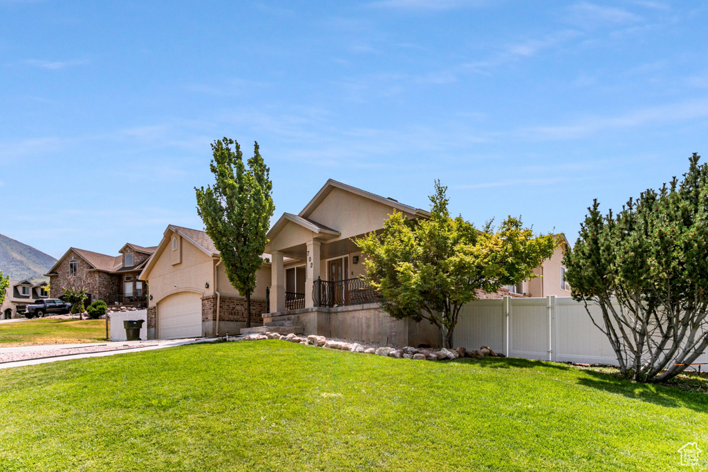 View of front of property featuring concrete driveway, a front lawn, covered porch, fence, and stucco siding