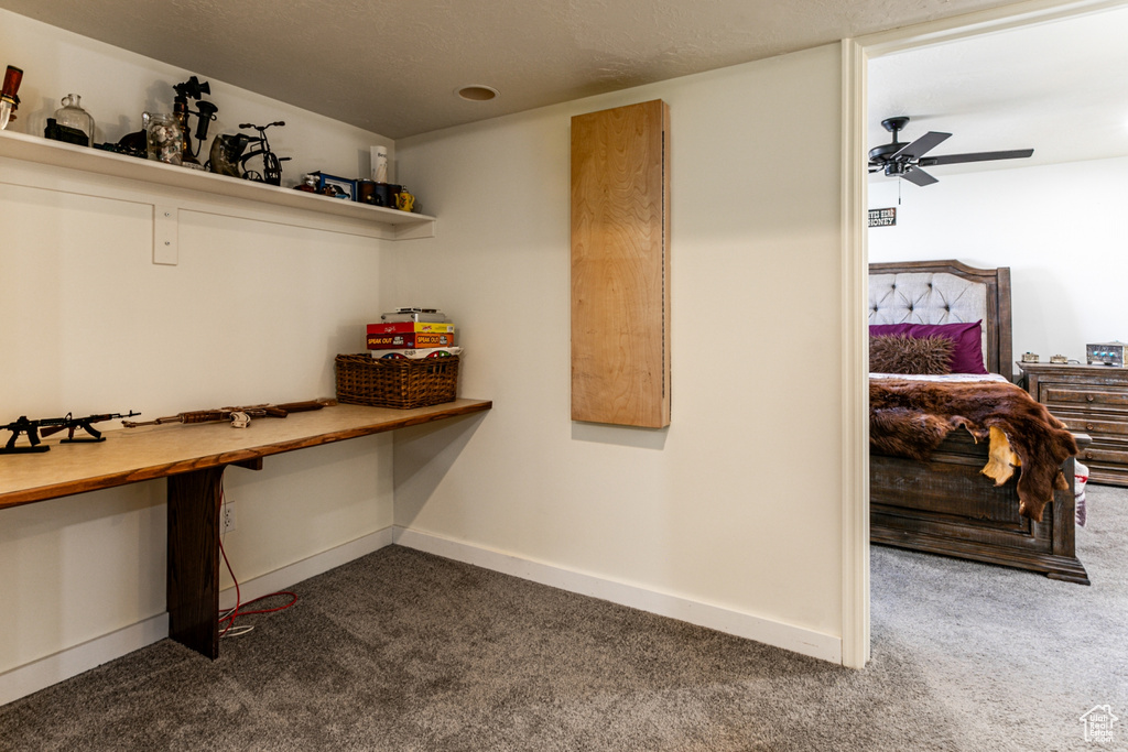 Interior space with built in desk, dark carpet, a ceiling fan, and baseboards