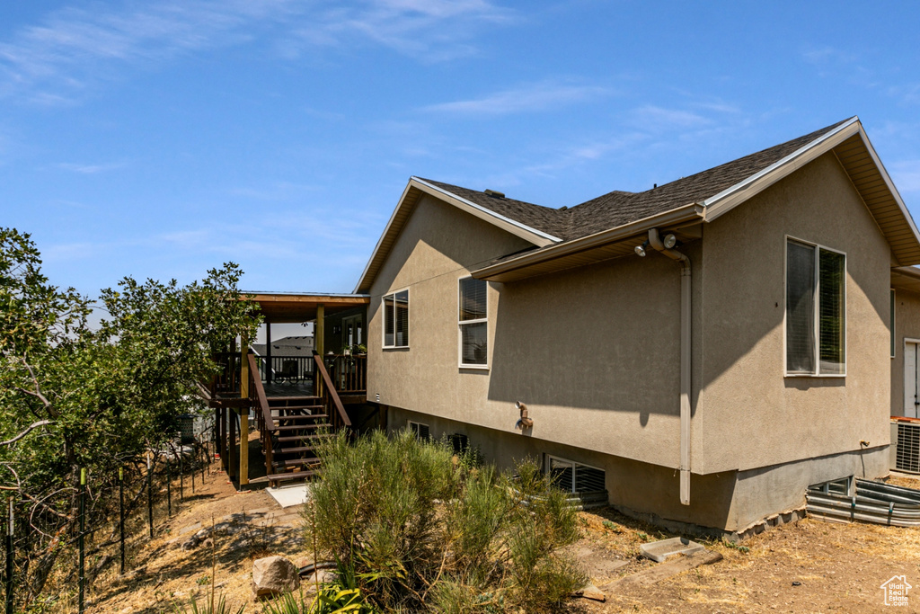 View of side of property with stairway, stucco siding, central AC unit, and a deck