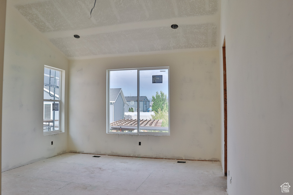Unfurnished room with plenty of natural light and lofted ceiling