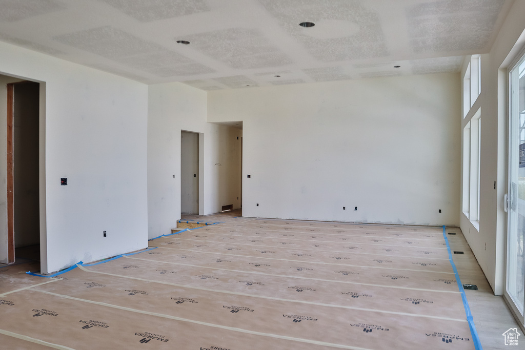 Empty room featuring light wood-type flooring and a high ceiling