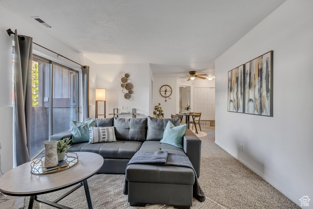 Carpeted living room with ceiling fan and baseboards