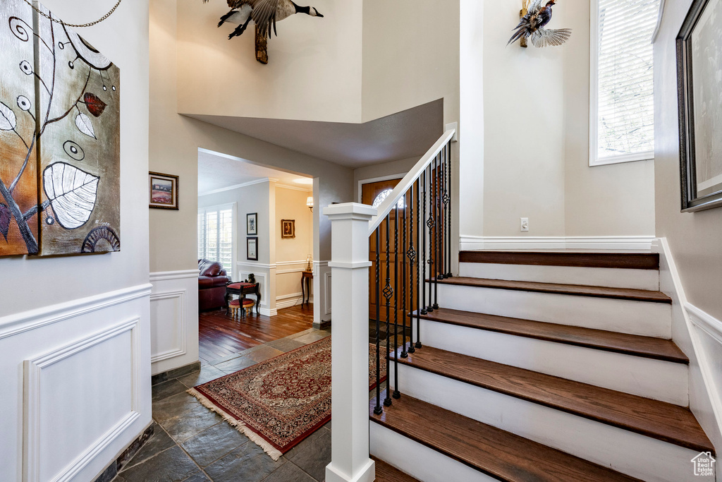 Stairs with stone finish floor, a high ceiling, a decorative wall, and a wainscoted wall