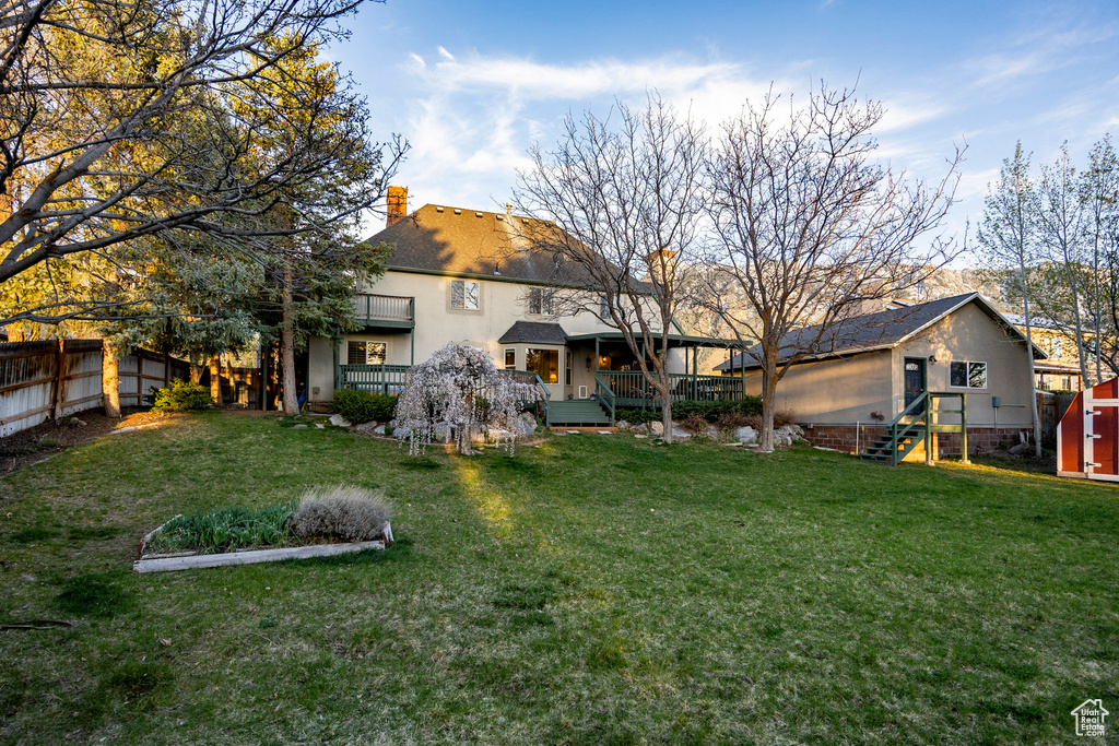 Rear view of house featuring a yard, a storage shed, fence, and a chimney