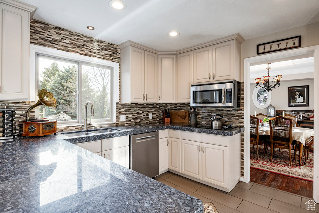 Kitchen with tile countertops, tasteful backsplash, appliances with stainless steel finishes, and a sink