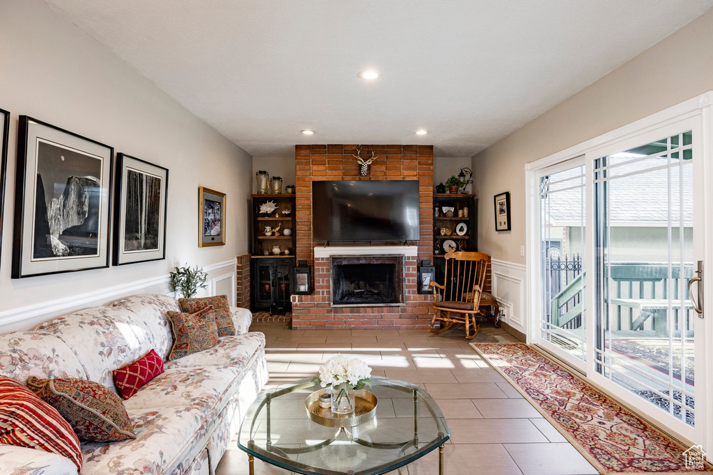 Living room featuring a wainscoted wall, a fireplace, a decorative wall, tile patterned flooring, and recessed lighting