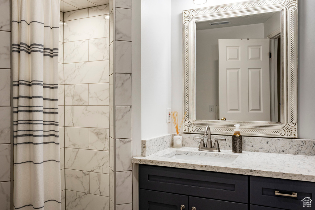 Bathroom featuring tiled shower, vanity, and visible vents