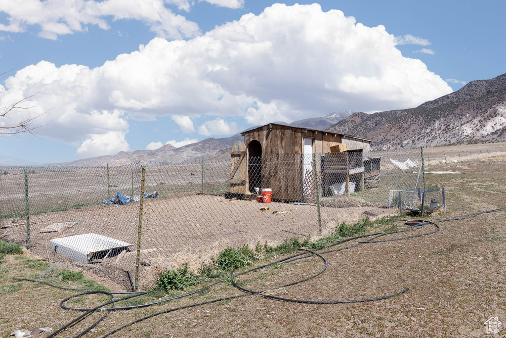 View of yard featuring an outbuilding, a mountain view, fence, and exterior structure