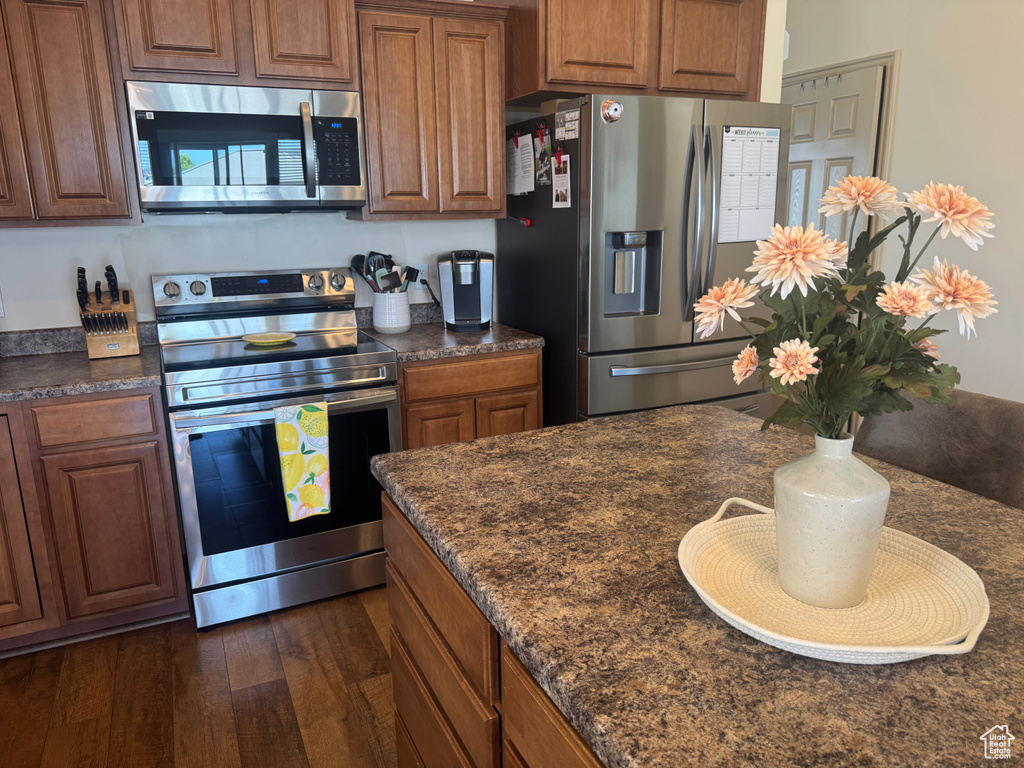 Kitchen featuring appliances with stainless steel finishes, dark countertops, and brown cabinetry