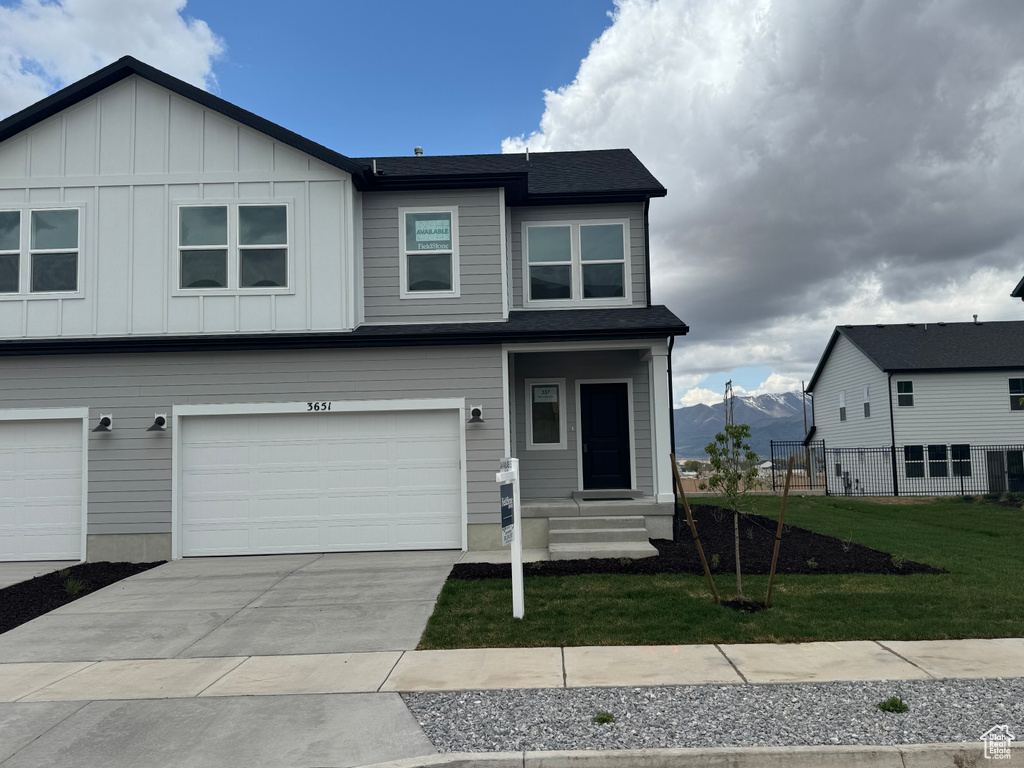 View of front facade featuring driveway, board and batten siding, fence, a front lawn, and a garage