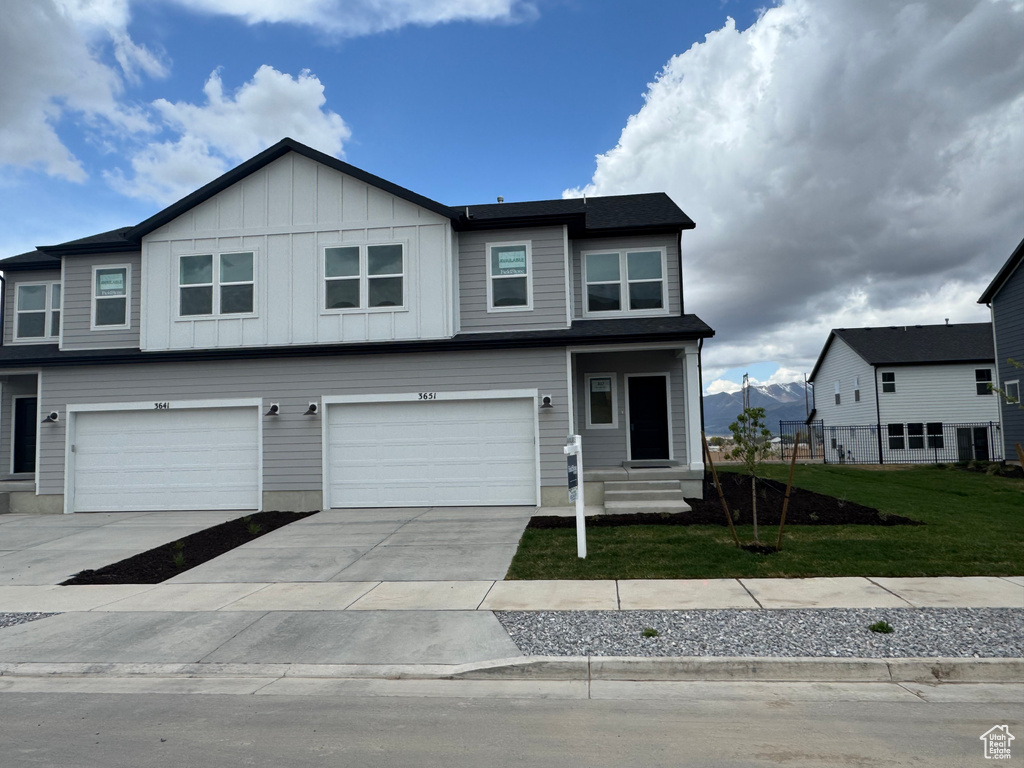 View of front of property with driveway, board and batten siding, a front yard, and an attached garage