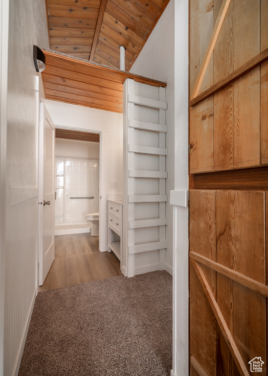 Spacious closet featuring lofted ceiling, carpet flooring, and wood finished floors
