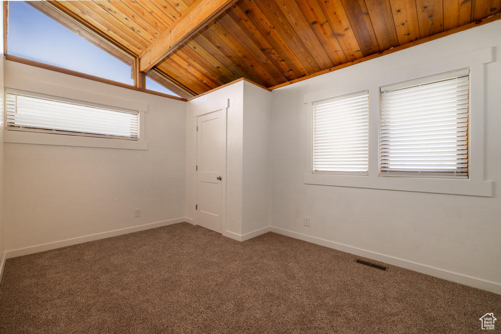 Carpeted spare room with baseboards, visible vents, vaulted ceiling with beams, and wood ceiling