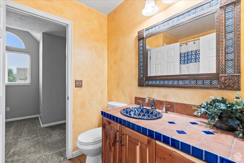 Bathroom with baseboards, vanity, curtained shower, and toilet