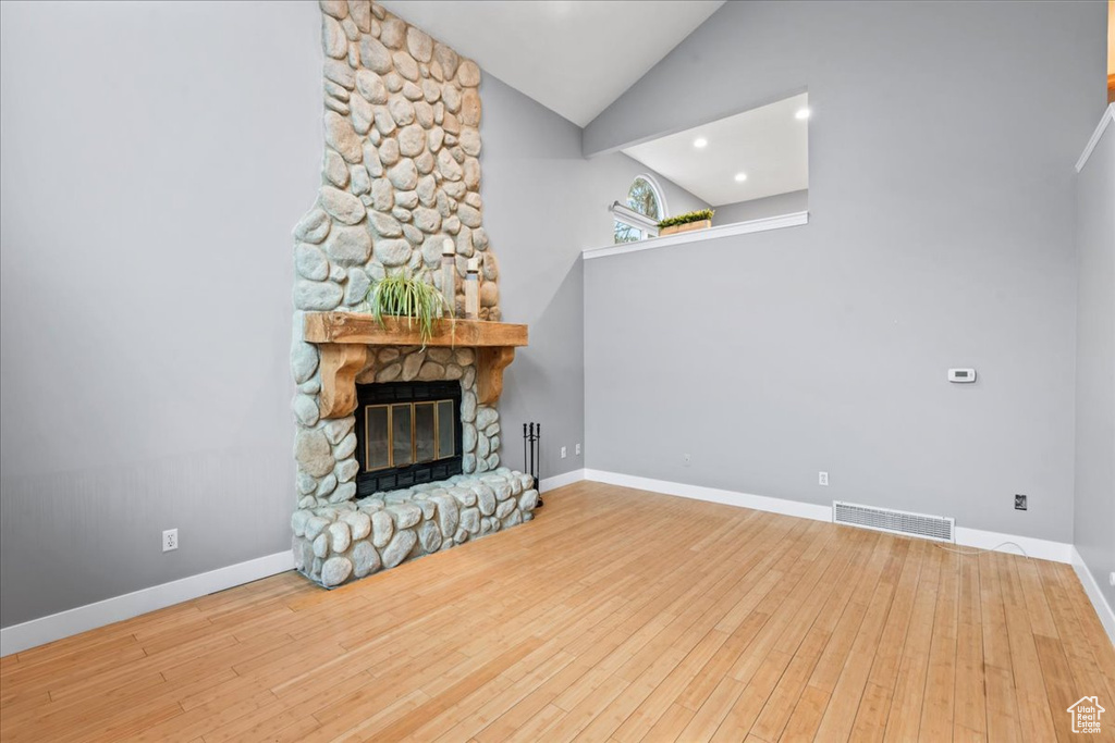 Unfurnished living room featuring hardwood / wood-style floors, baseboards, visible vents, and a fireplace