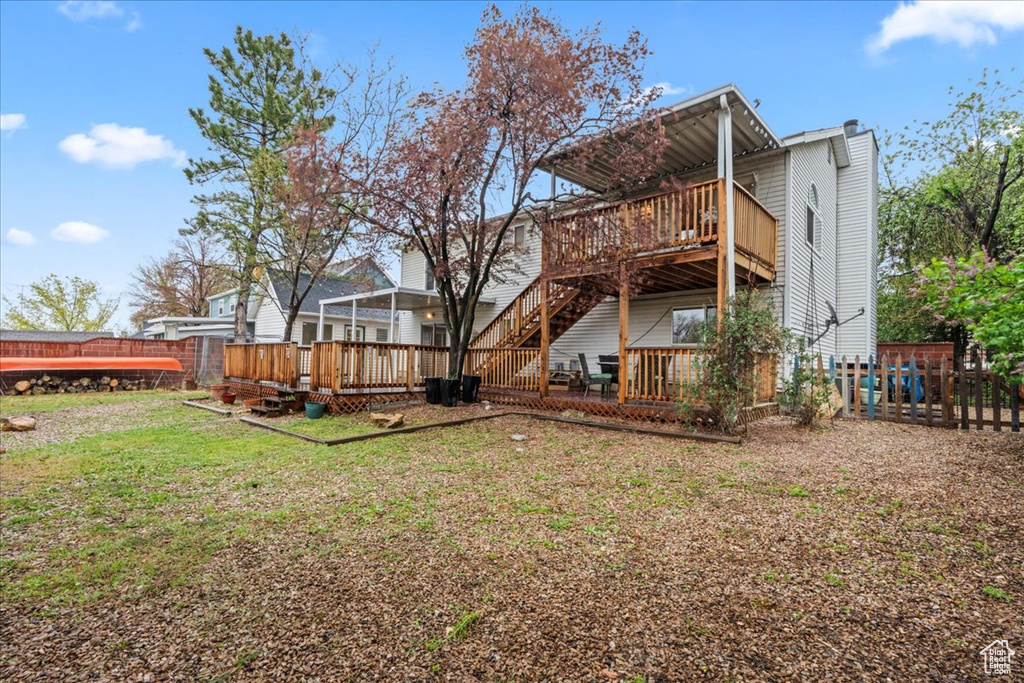Rear view of house with a lawn, fence, and a deck