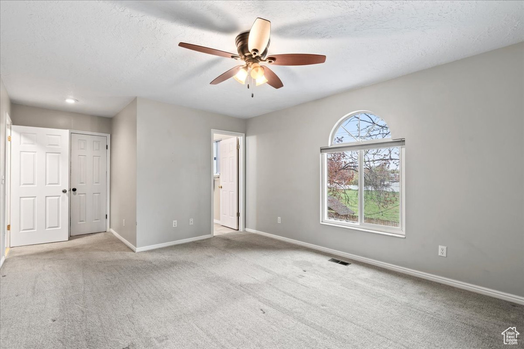 Interior space with a textured ceiling, visible vents, a ceiling fan, and baseboards
