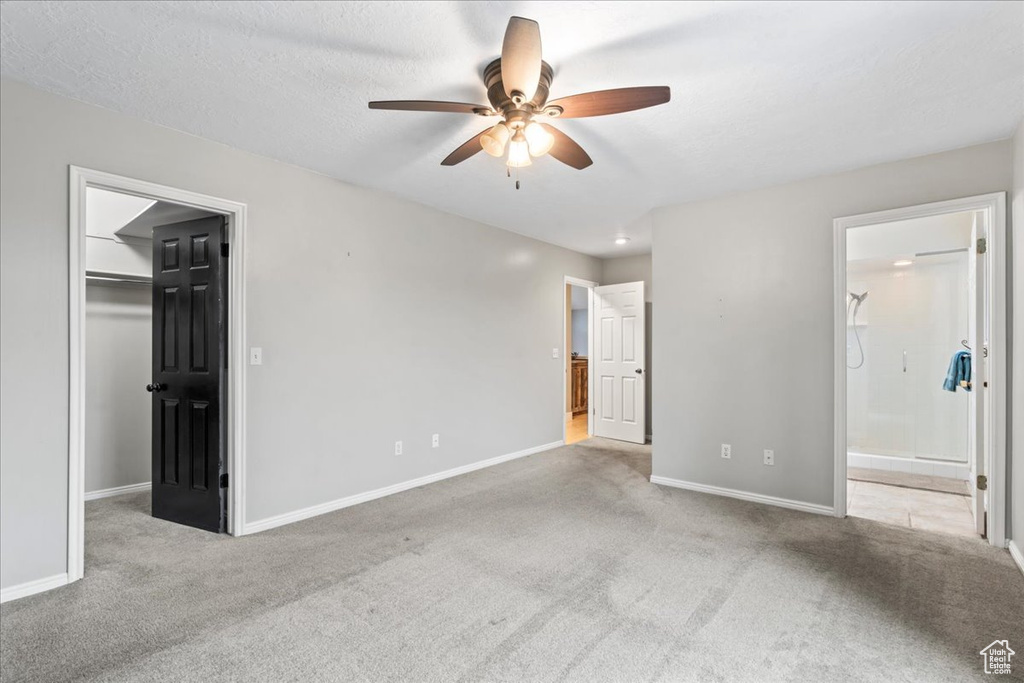 Unfurnished bedroom featuring baseboards, a spacious closet, a closet, ensuite bath, and carpet floors