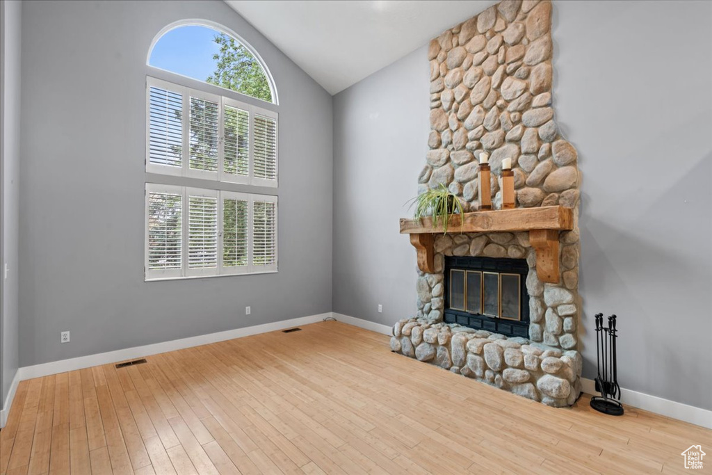 Unfurnished living room with a fireplace, vaulted ceiling, hardwood / wood-style floors, and baseboards