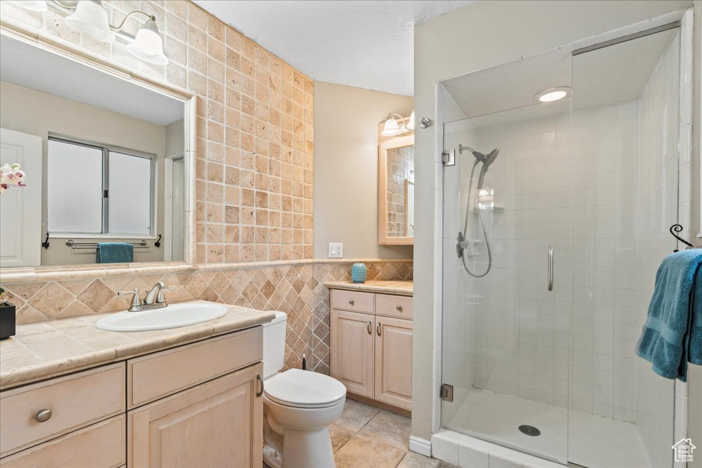 Full bath with tile walls, vanity, tile patterned flooring, and a stall shower