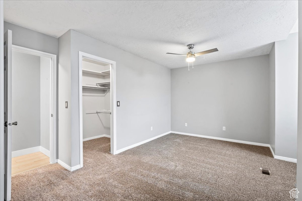 Unfurnished bedroom featuring a spacious closet, ceiling fan, carpet floors, baseboards, and visible vents