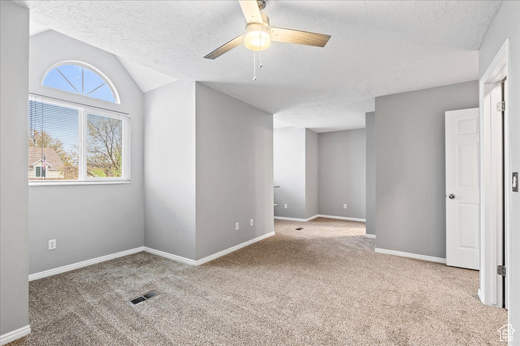 Spare room featuring a ceiling fan, visible vents, carpet, and a textured ceiling