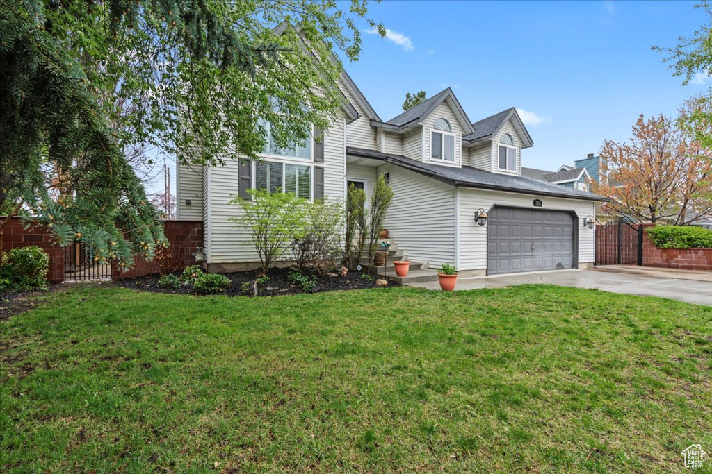 View of front of house featuring a front yard, concrete driveway, and fence