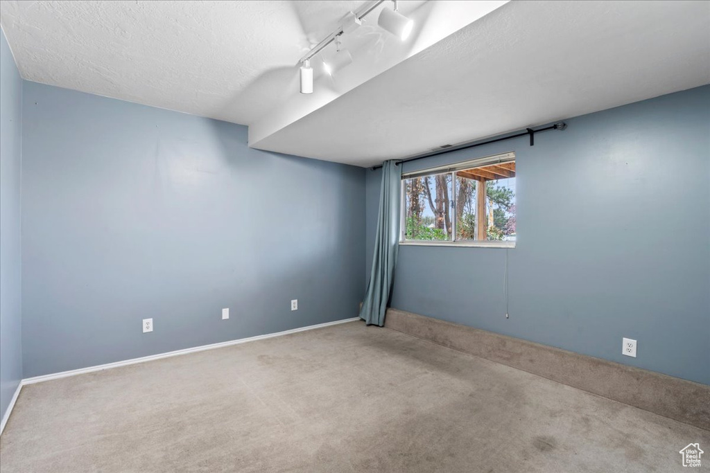 Spare room featuring track lighting, baseboards, carpet, and a textured ceiling