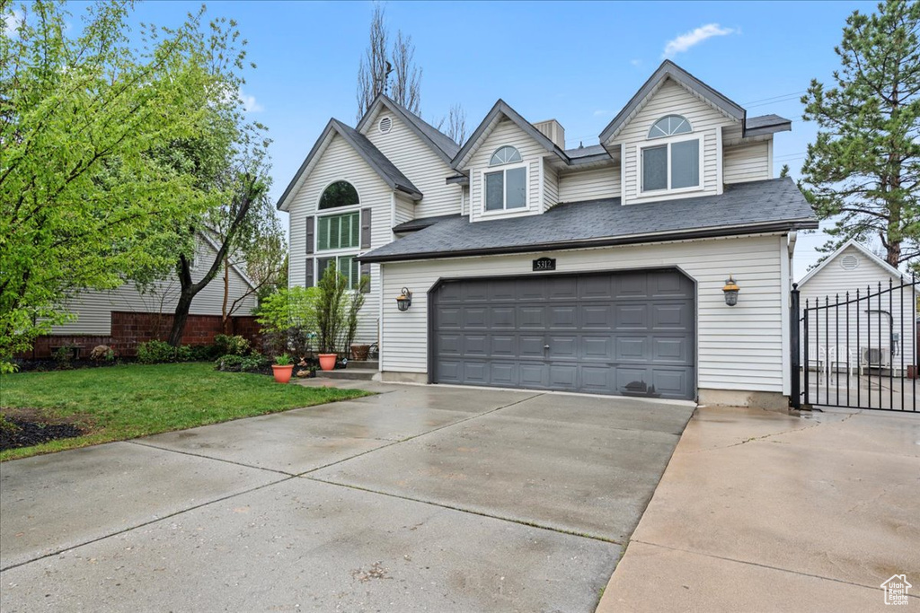 View of front of property with concrete driveway, a front lawn, fence, and a garage