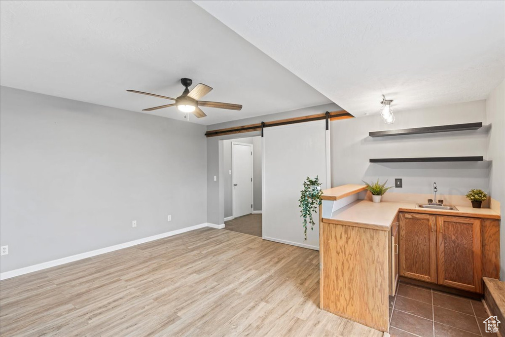 Kitchen with a barn door, open shelves, a sink, ceiling fan, and light countertops