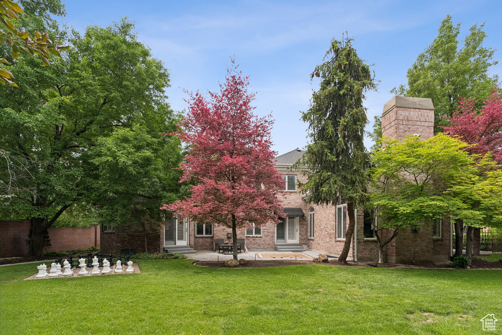 Back of house with a patio area, brick siding, a lawn, and entry steps
