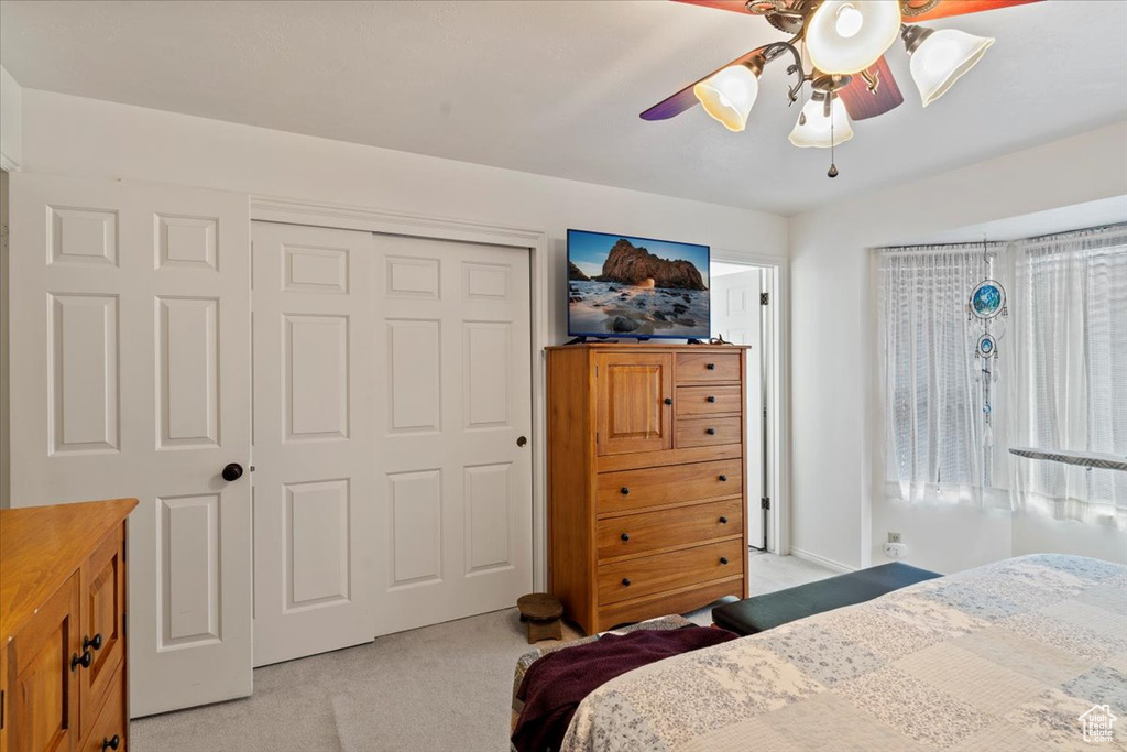 Bedroom with light carpet, a closet, and ceiling fan