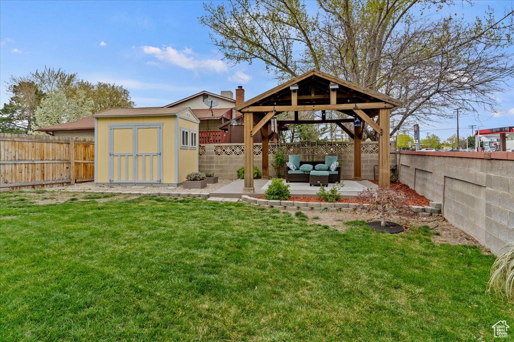View of yard featuring a storage shed, an outdoor hangout area, a gazebo, and a fenced backyard